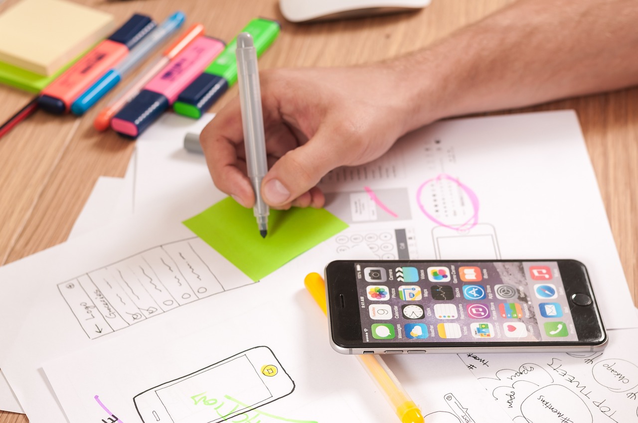 Person writing something in paper and a phone is along with it